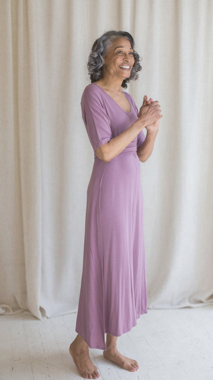 Load image into Gallery viewer, Woman wearing womens hospital gown, patient in lilac wrap dress style, standing with hands clasped
