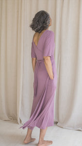 Woman wearing hospital patient gown, patient in lilac modal wrap dress, worn reversible, hand in pockets back view