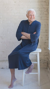 Man wearing mens hospital gown in cotton Henley in midnight blue, patient with arms crossed sitting on a stool