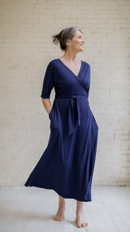 Load image into Gallery viewer, Woman wearing womens hospital gown, patient in blue wrap dress standing with hands in pockets, front
